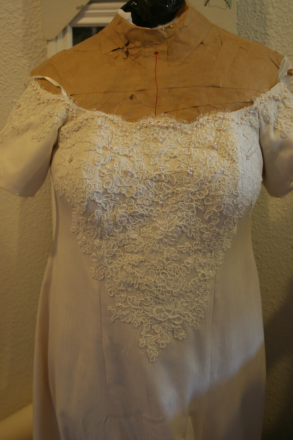 An interim view of the wedding dress, with pearls and lace still in the design stages.