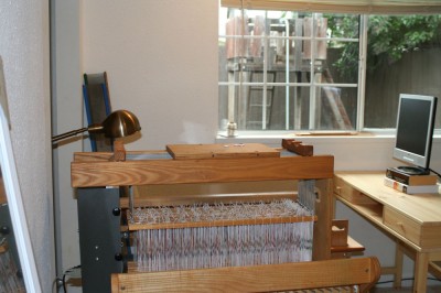 The loom and bench in the new weaving studio.  Barely visible in the right side is the computer desk for the computer that will drive the loom (and also be my home office when I'm working).