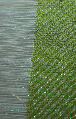 early part of the weaving, green tencel and gold embroidery thread weft, showing the sparkle of the opalescent transparent nylon thread