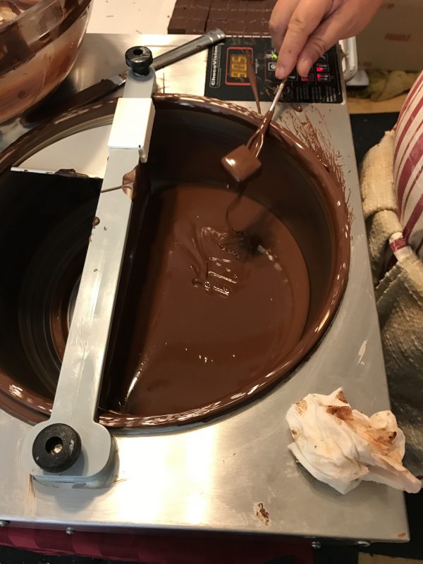 removing excess chocolate from a freshly-dipped bonbon